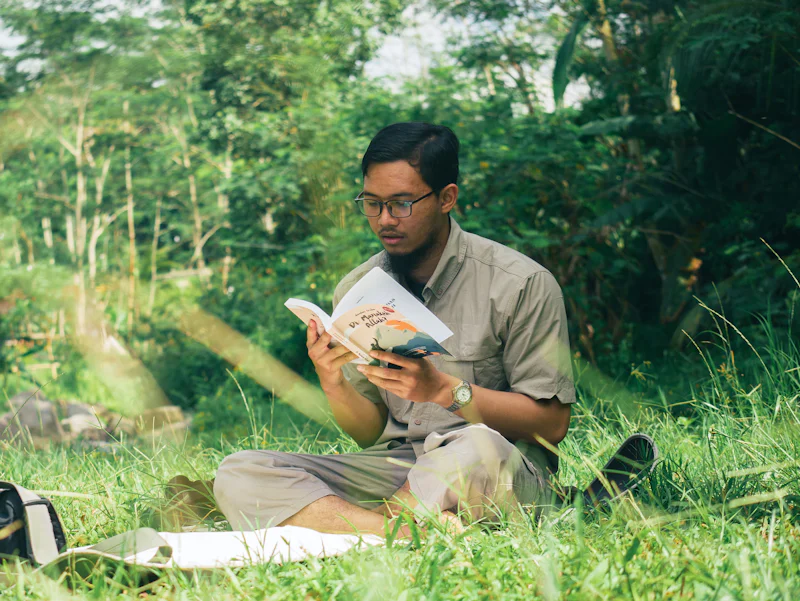 Un homme assis dans l’herbe en train de lire