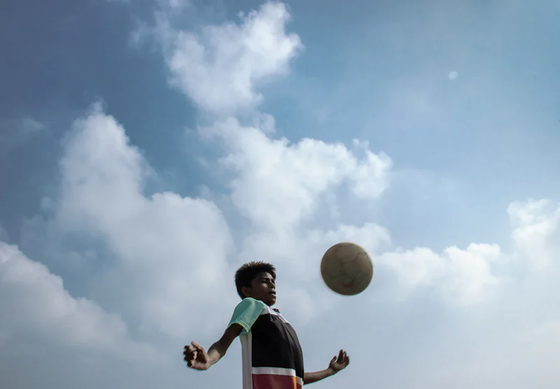 Un garçon jouant au football sous un ciel lumineux